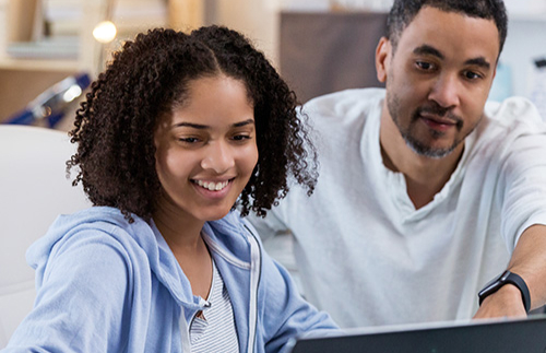 Father and daughter working on their laptop at home